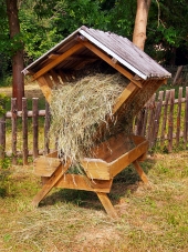 Comedero de madera protegido completamente lleno de heno